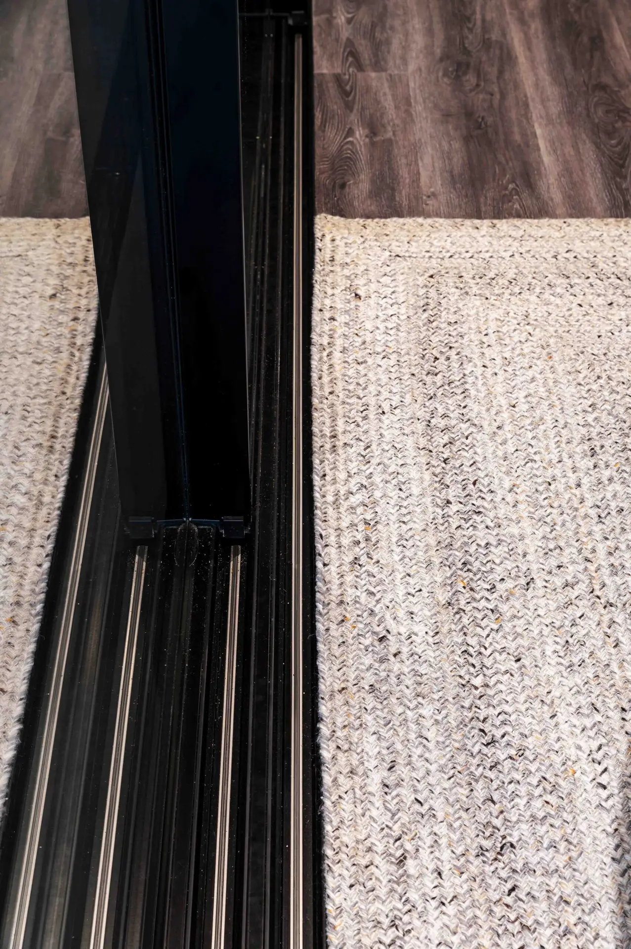 Shows a hidden sliding door track recessed into the floor for slim sight lines.